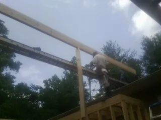 Carpenter setting a ridge beam over a new addition frame — Ice Dam Removal by Roofing Brothers in Zenia