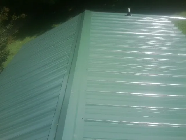 New green metal panels meeting at the ridge of a roof — Flat Roof Repair work by our crew in Zenia