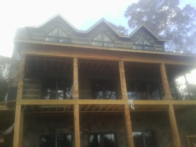 Dormers and porch framing on a large log home under construction — Roof Coating work by our crew in Zenia