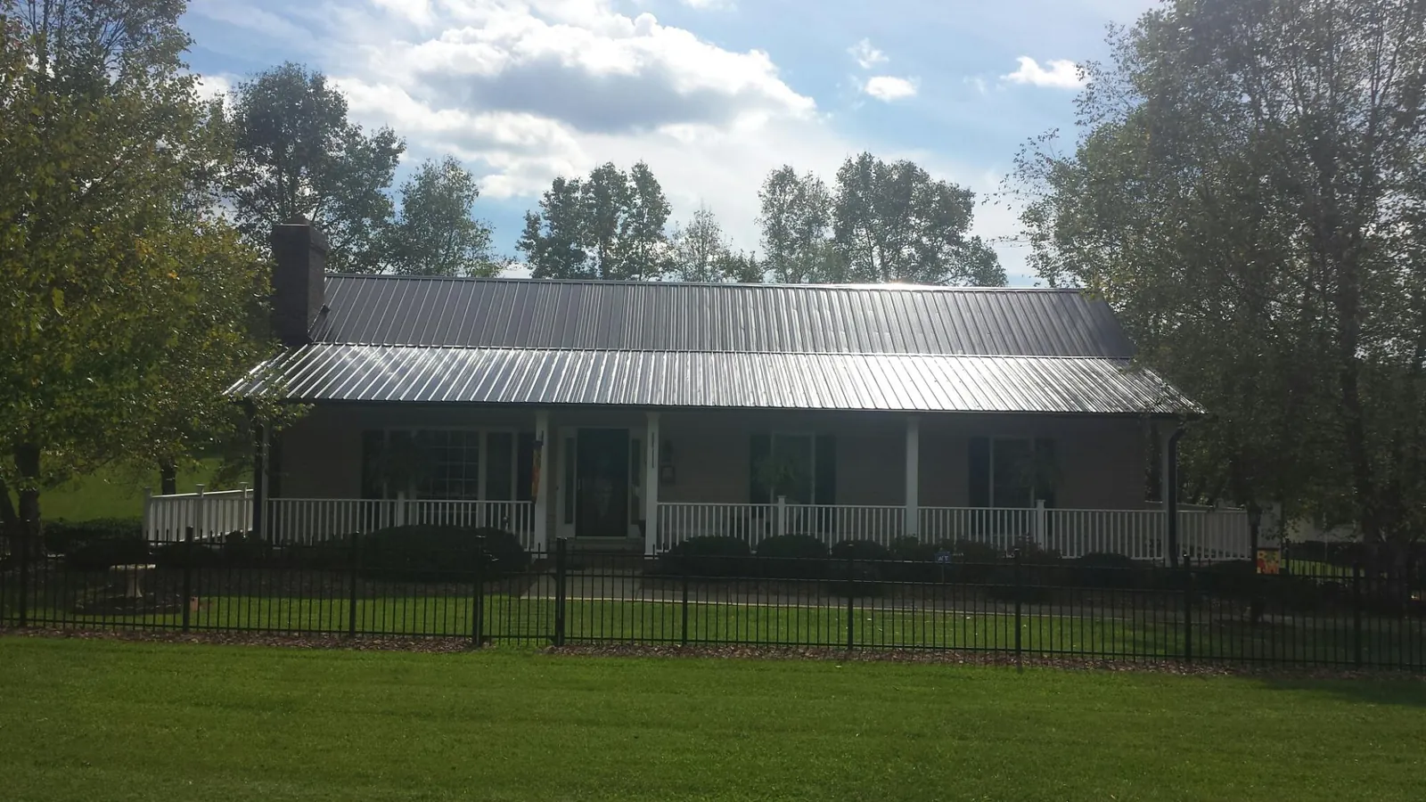 Gray metal roof on a brick ranch with a full width front porch — Gutter Guard Installation work by our crew in Zenia