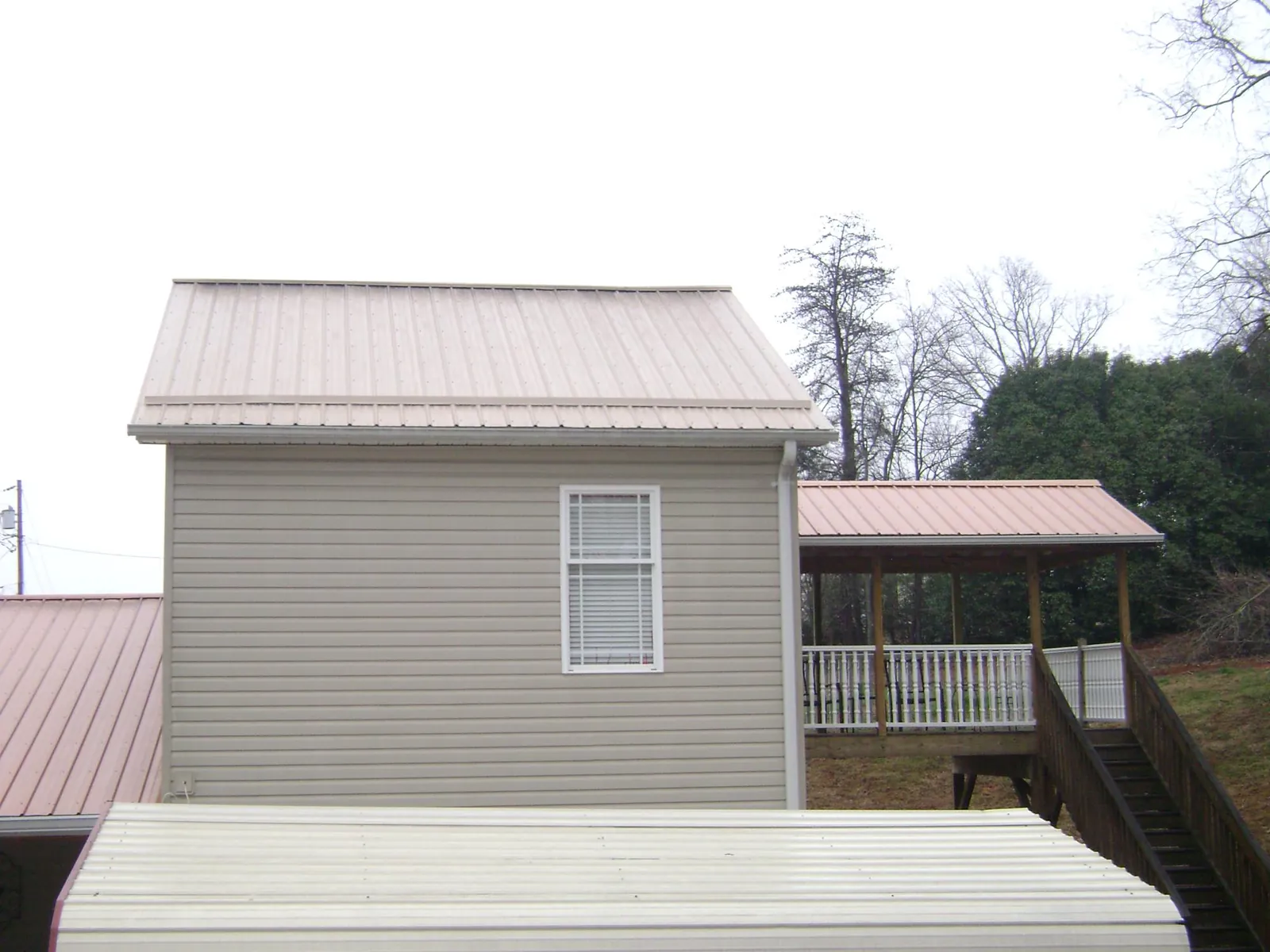 Tan metal roofs on a two story addition and attached porch, from a Roof Replacement job in Zenia