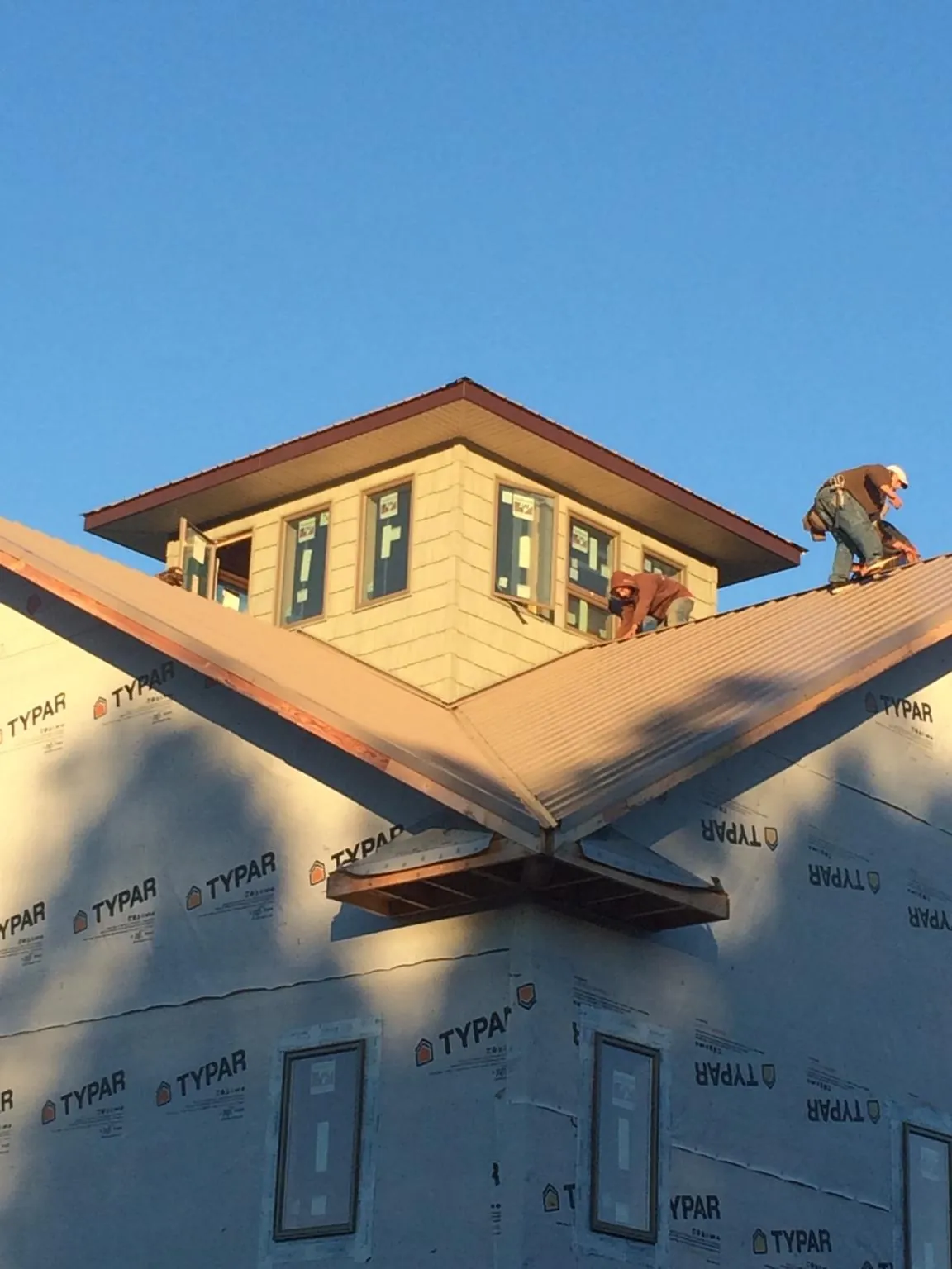Roofers working around a rooftop cupola on a new metal roof at sunset — Roof Waterproofing in Zenia by Roofing Brothers